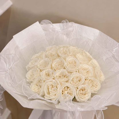 Bouquet of white roses wrapped in cellophane on a neutral background