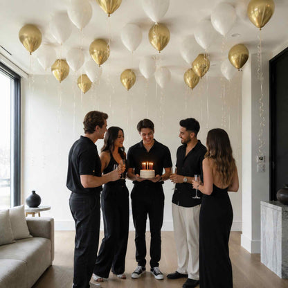 Group of people celebrating a birthday with balloons in a modern living room.