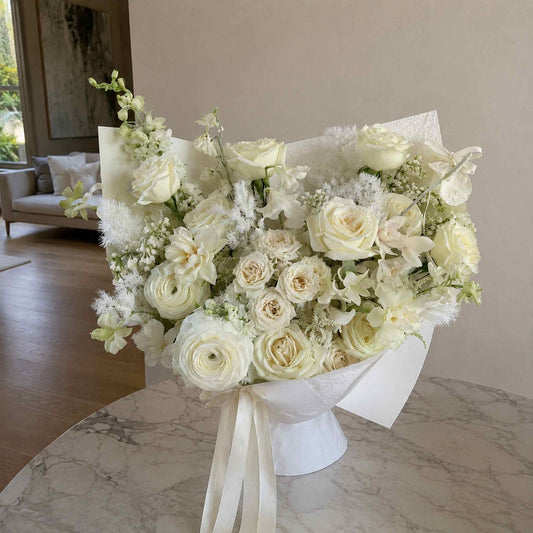 Bouquet of white and light green flowers on a marble surface with a neutral background