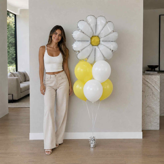 Woman holding a bouquet of balloons shaped like daisies in a modern living room.