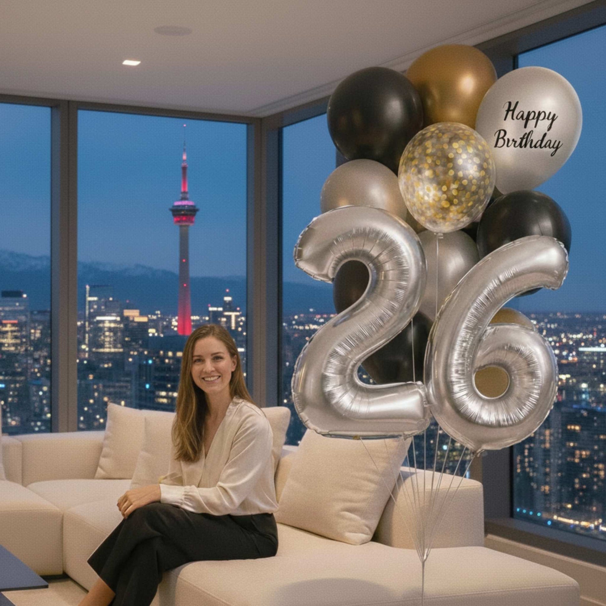 Woman sitting on a couch with 'Happy Birthday' and number balloons in a cityscape at night.