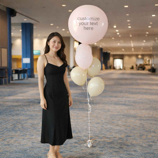 Woman in a black dress holding balloons with customizable text in an indoor setting.